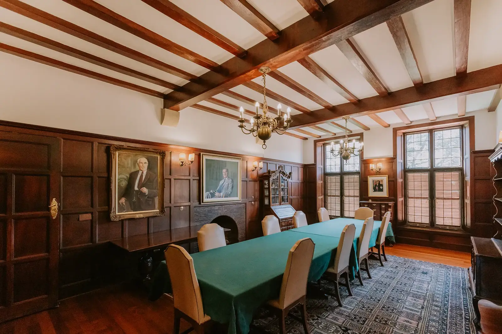 The Council Room at Glenshiel, panelled, with a piano, portraits and chandeliers
