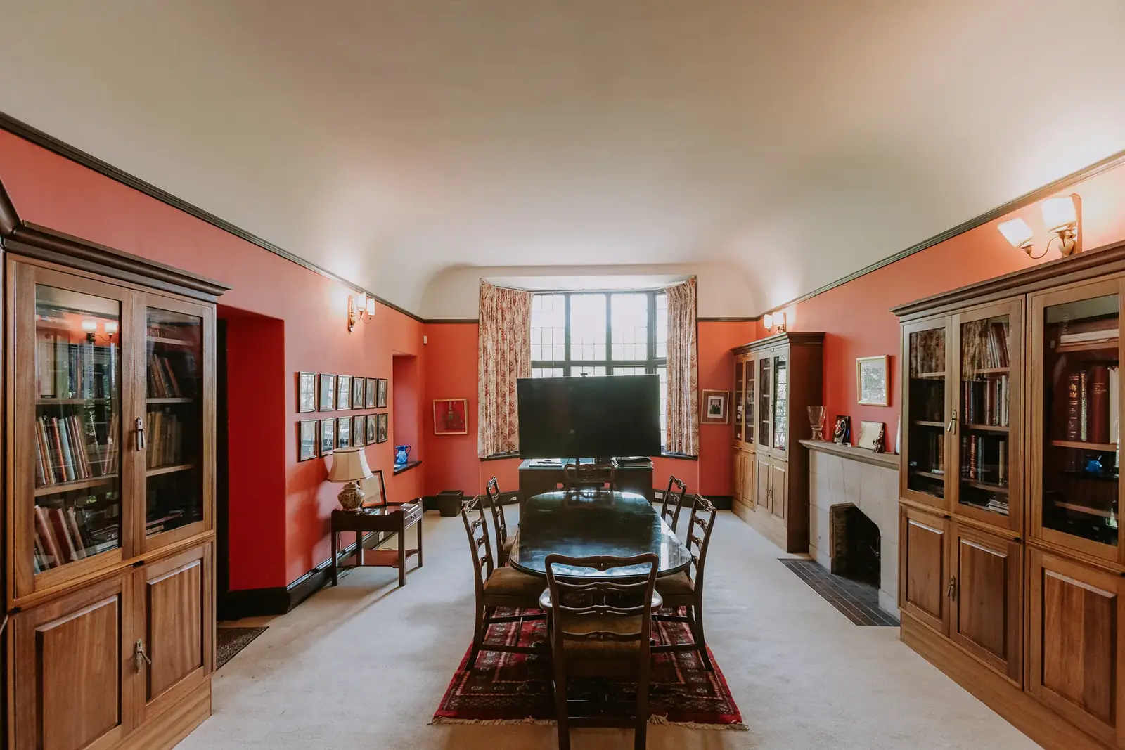 The Library at Glenshiel, lined with bookcases against warm red walls