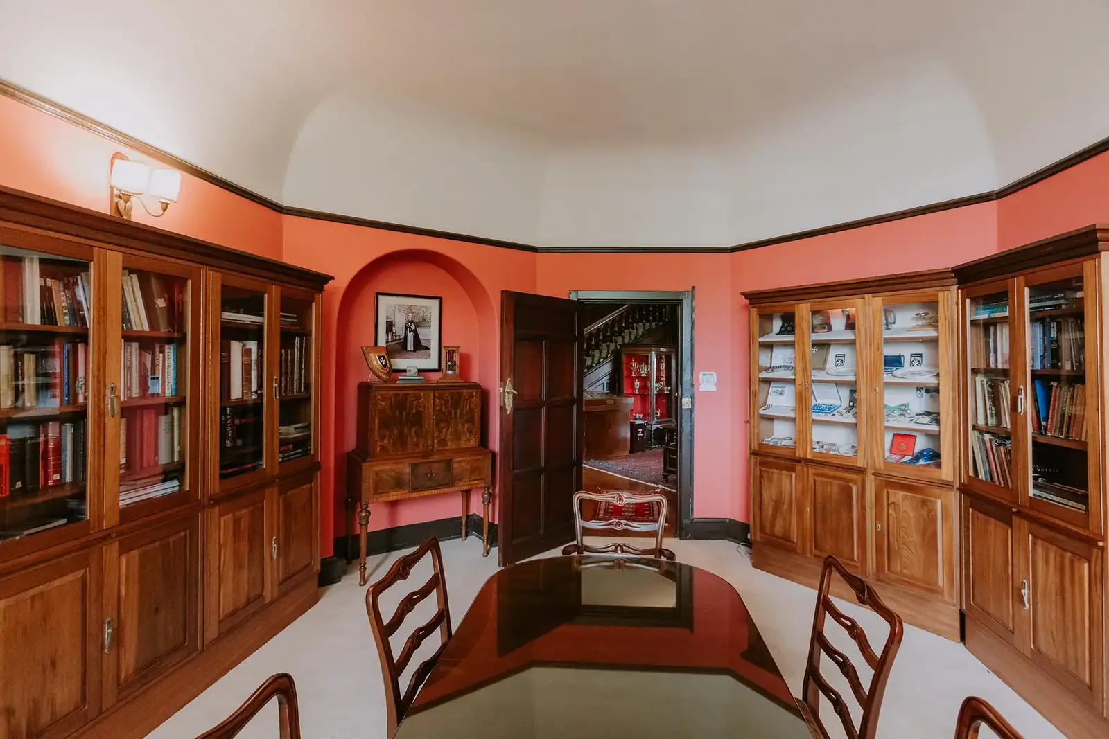 The Library at Glenshiel, lined with bookcases against warm red walls